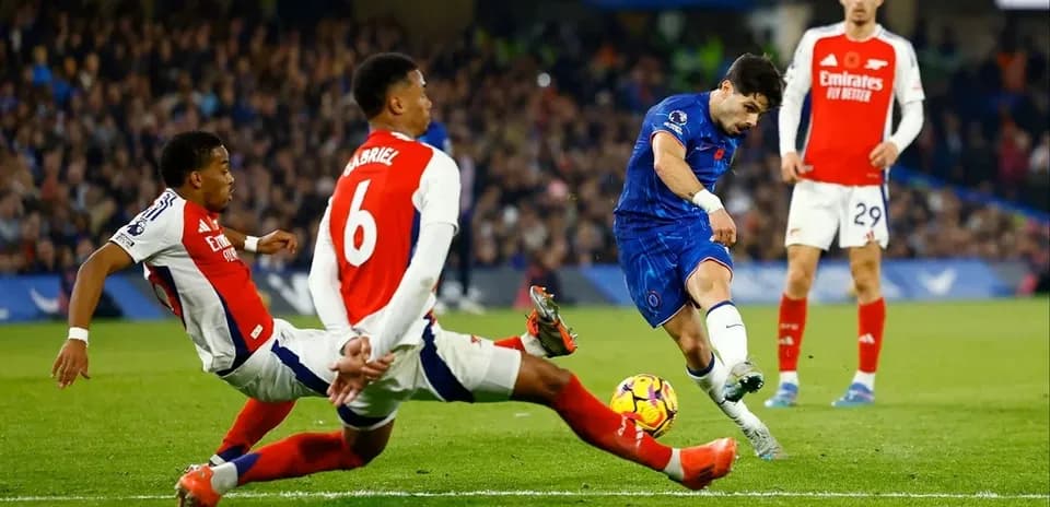 Chelsea player shooting past two Arsenal defenders