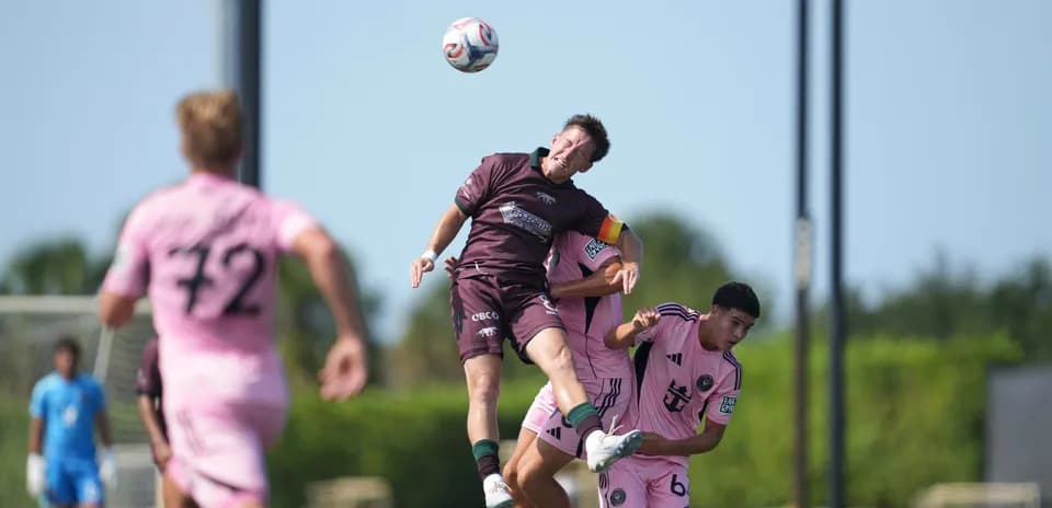 Player heading the ball during MLS Next Pro match