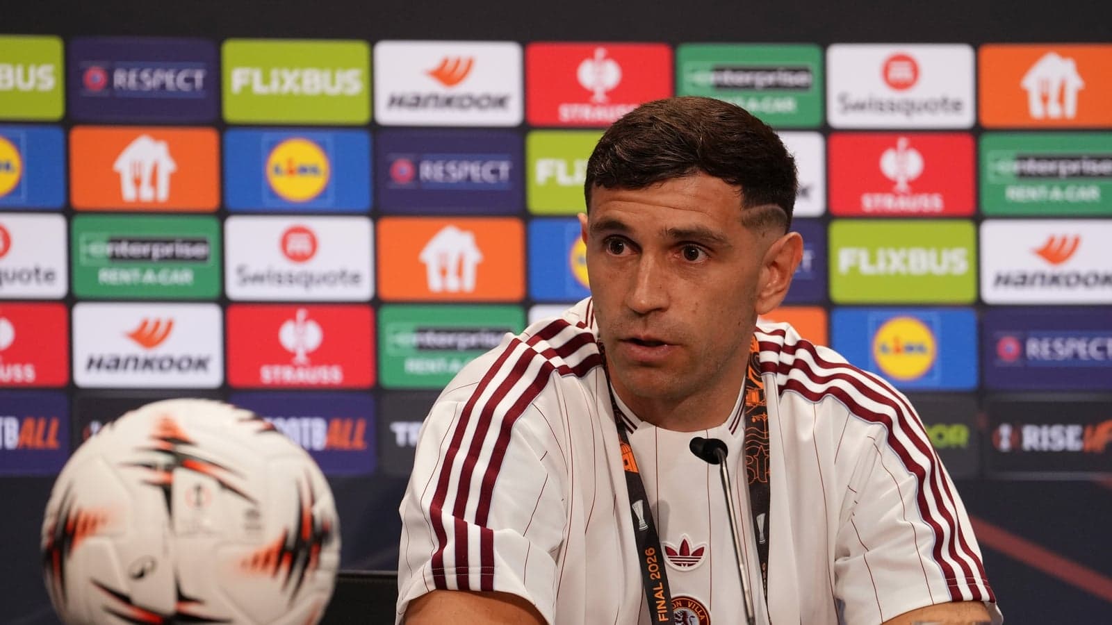 Player speaking at press conference with a football
