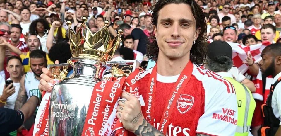 Player holding Premier League trophy with fans celebrating