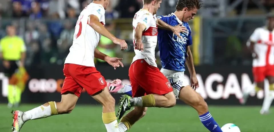Genoa player challenging Como opponents for the ball
