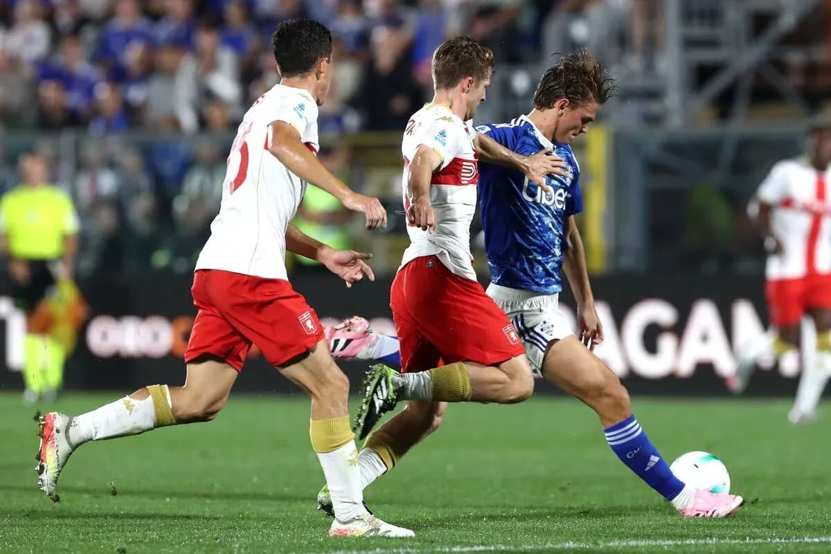 Genoa player challenging Como opponents for the ball