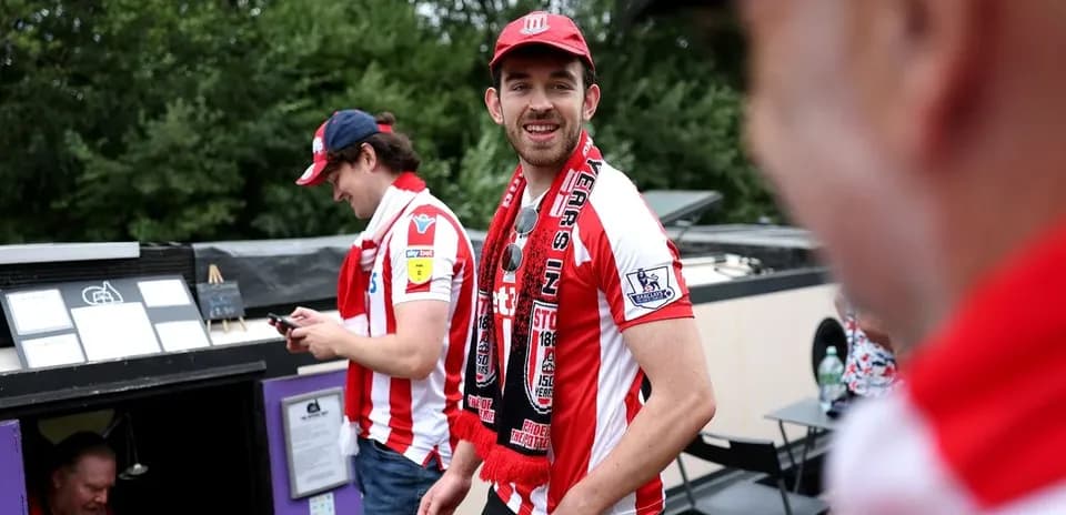 Fans wearing team jerseys and scarves outside venue
