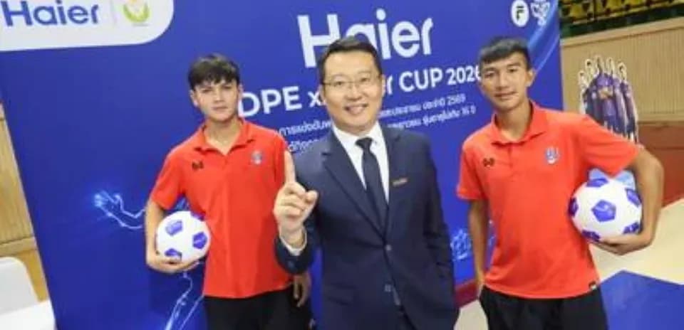 Two young players and a man posing with soccer balls