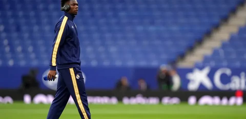 Player walking on pitch wearing headphones before match