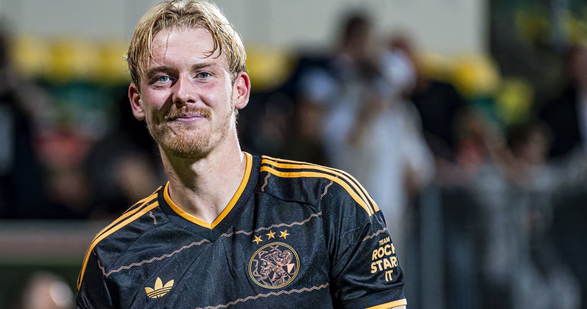 Player smiling in Ajax football jersey after match