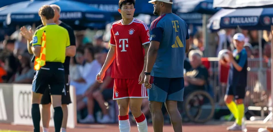 Bayern Munich player conversing with coach on sideline