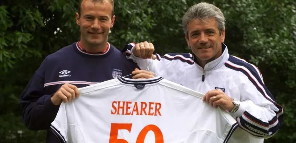 Two men holding a football shirt with 'SHEARER 50'