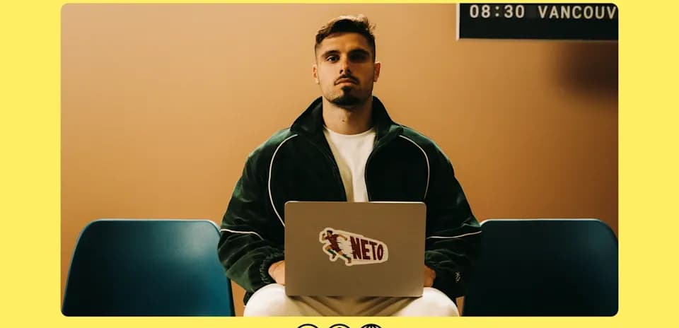 Person sitting with laptop displaying 'NETO' sticker