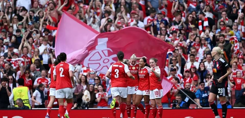 Arsenal women celebrating a goal with fans cheering