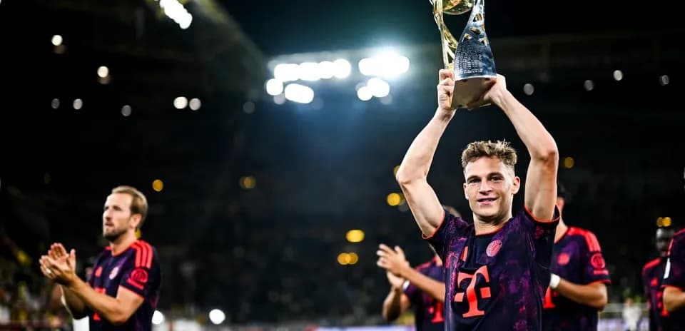 Player holding trophy with teammates celebrating behind