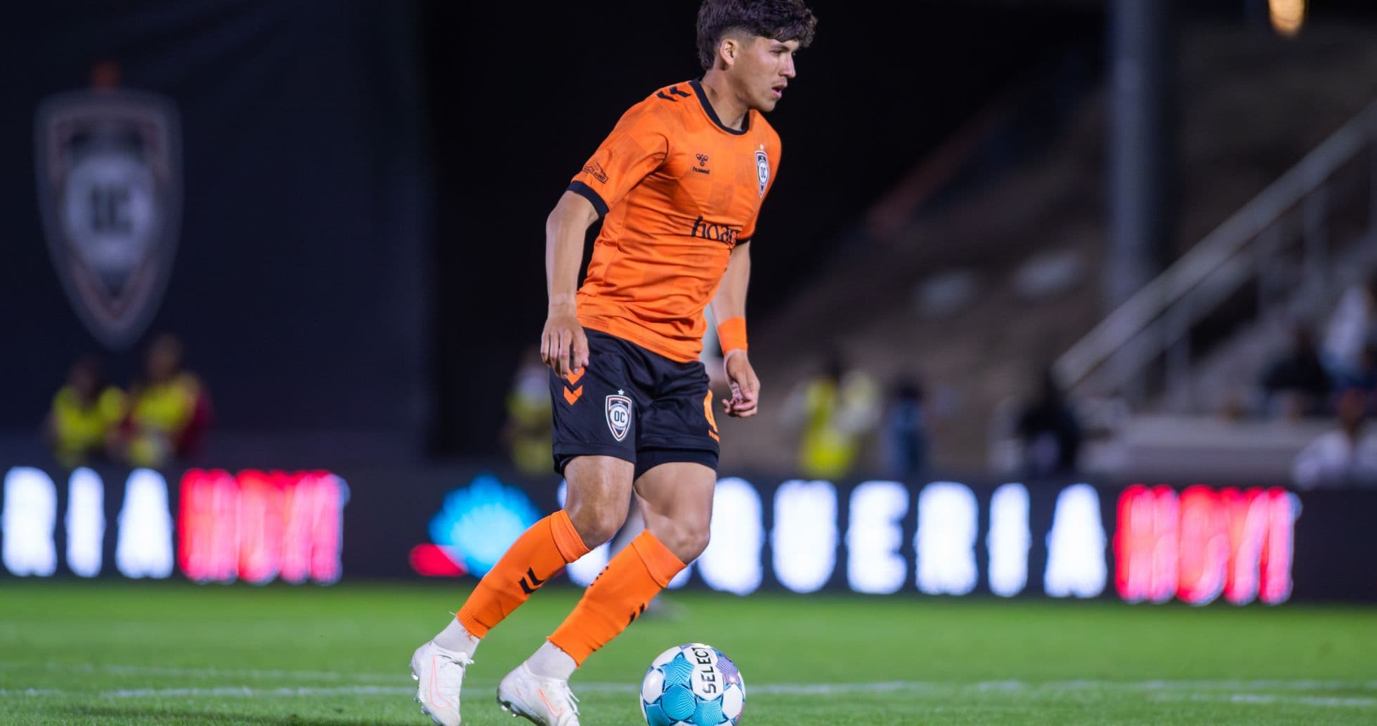 Orange County SC player dribbling ball on field