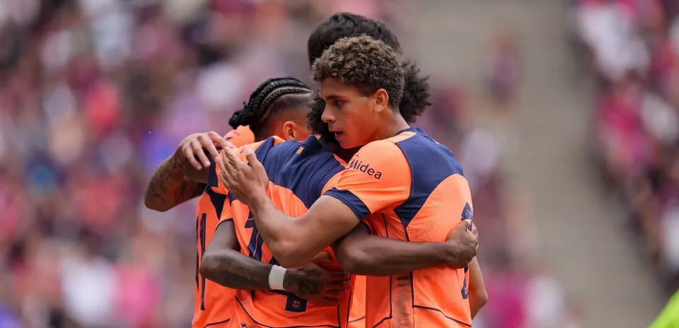 Players celebrating a goal in orange jerseys