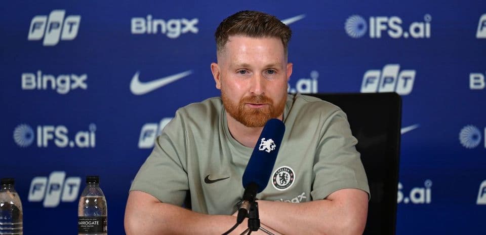Manager speaking at press conference with team logo