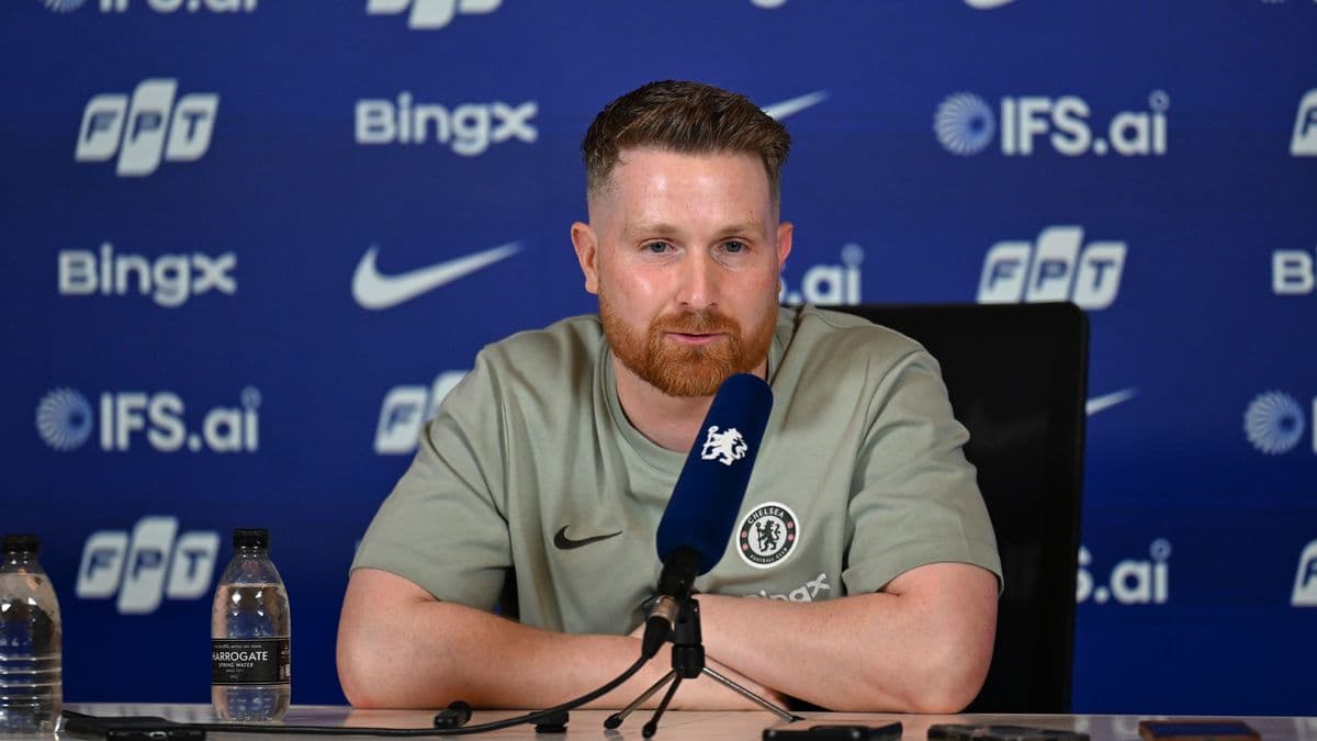 Manager speaking at press conference with team logo
