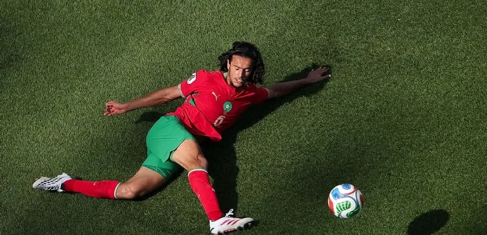 Moroccan player sliding on grass toward soccer ball