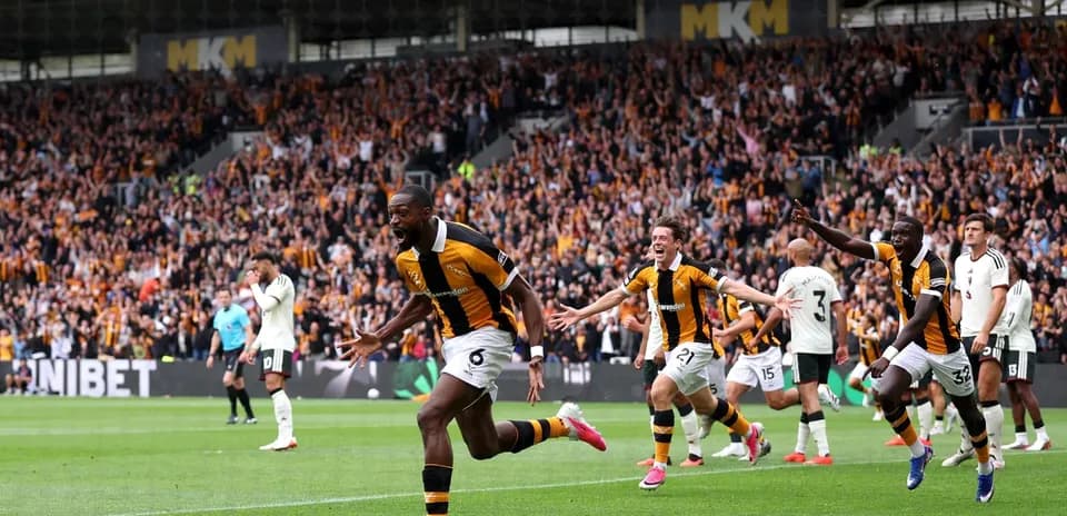 Player celebrating goal with teammates and fans
