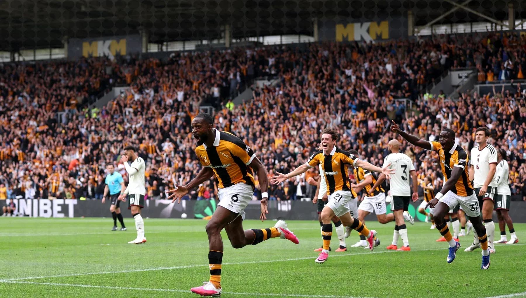 Player celebrating goal with teammates and fans
