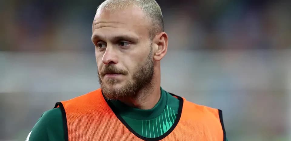Player in warm-up jersey on sidelines during match