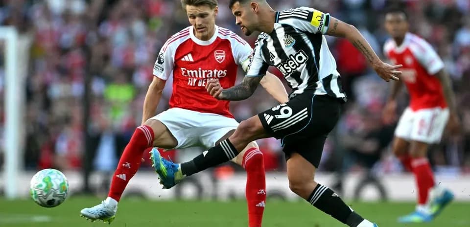 Newcastle player kicking ball past Arsenal opponent
