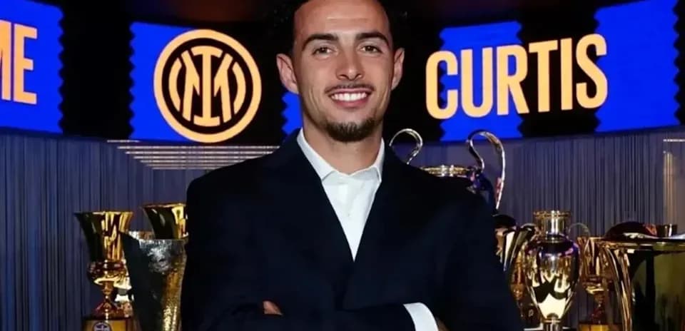 Person posing with trophies at event backdrop