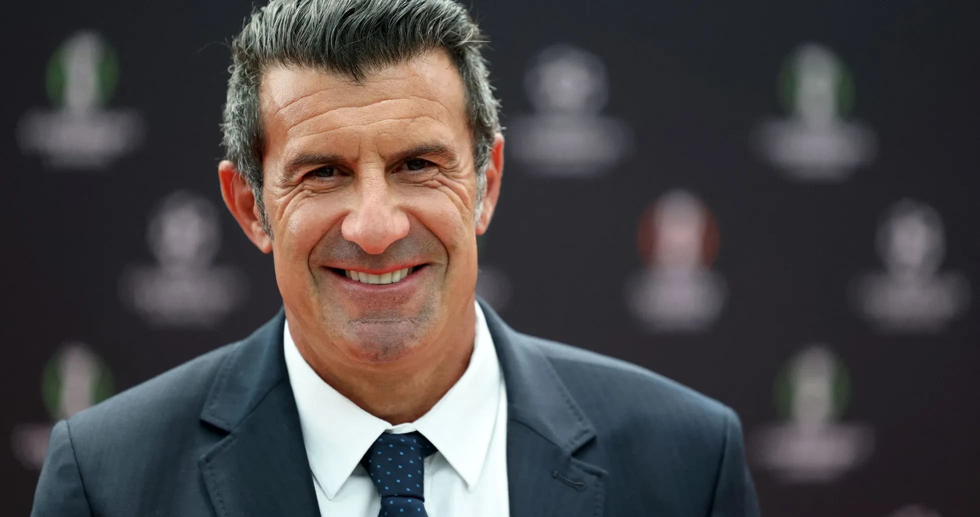 Smiling man in suit at event backdrop