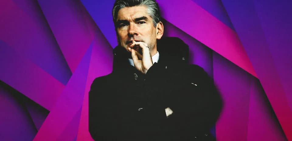Man in black coat with hand on chin