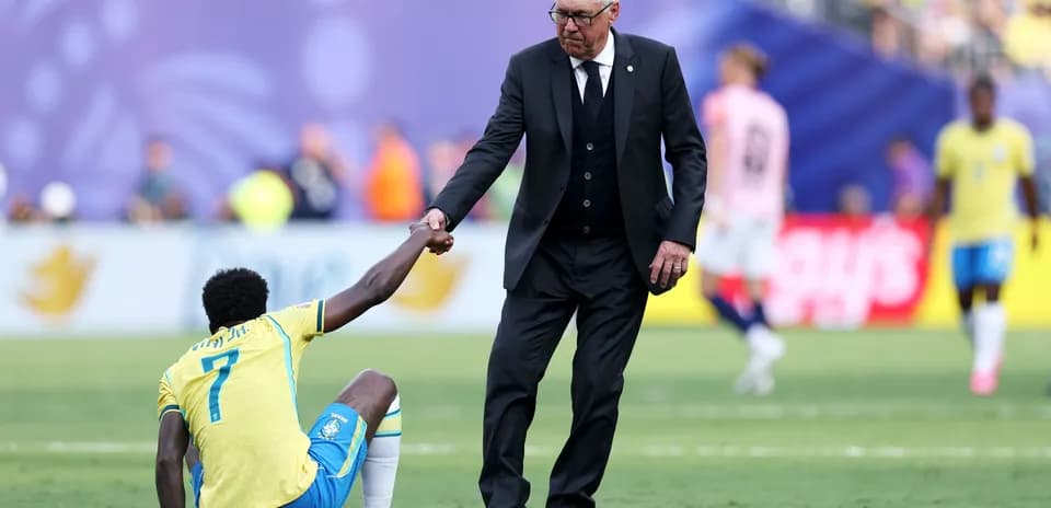Coach assisting player sitting on the field