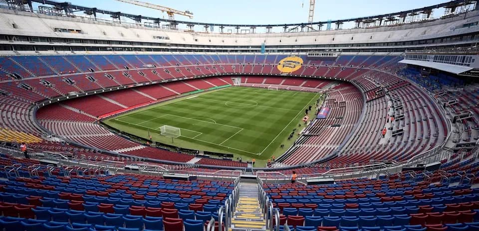 Empty stadium with green pitch and seating areas