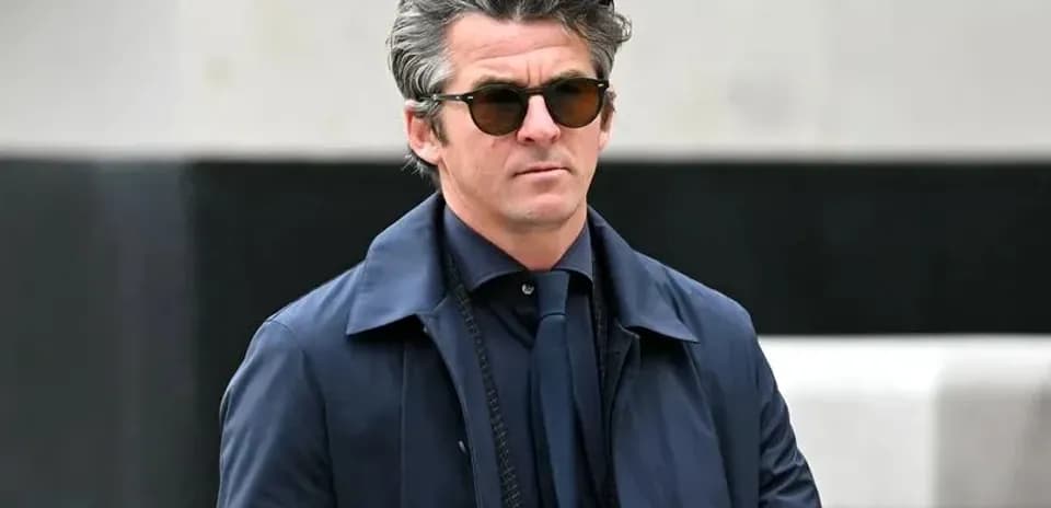 Man in sunglasses walking outdoors in a coat
