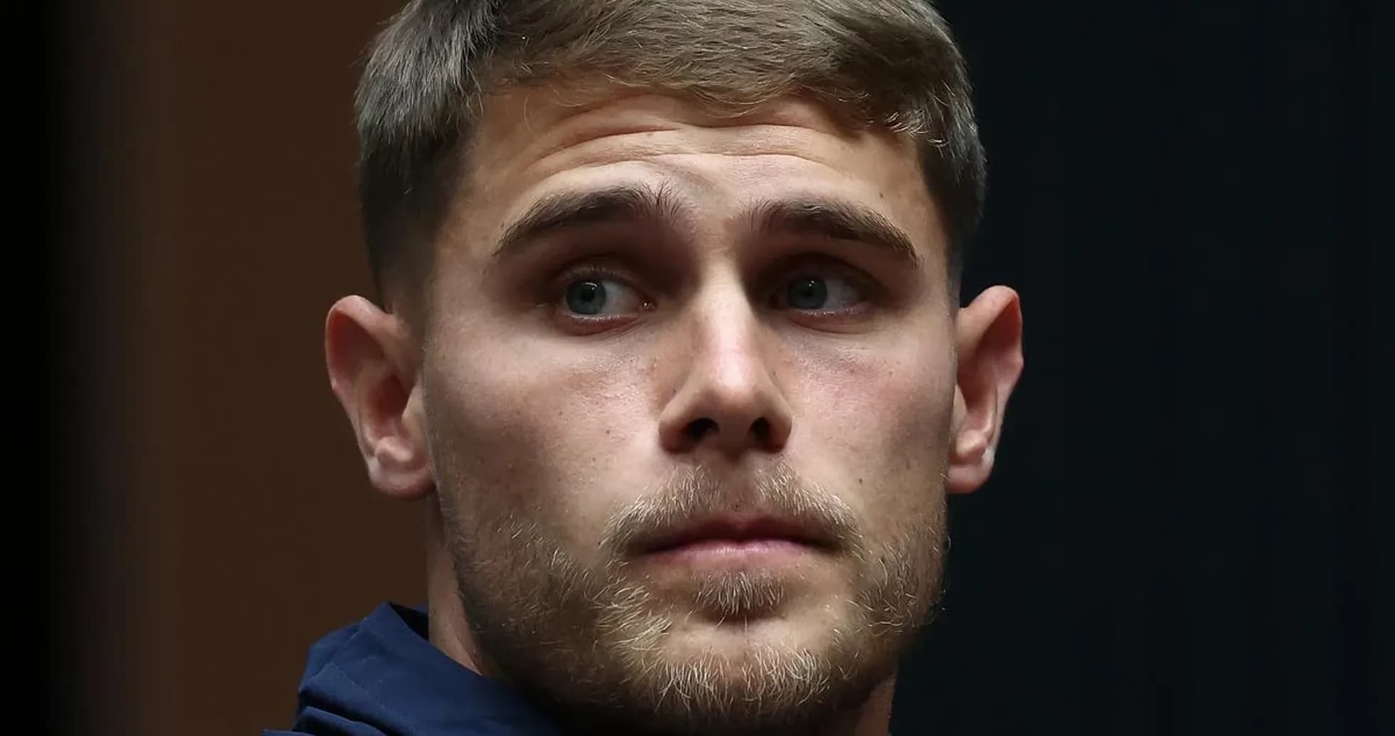 Athlete in a blue jacket looking thoughtfully