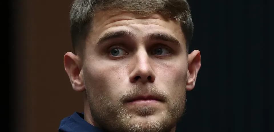 Athlete in a blue jacket looking thoughtfully