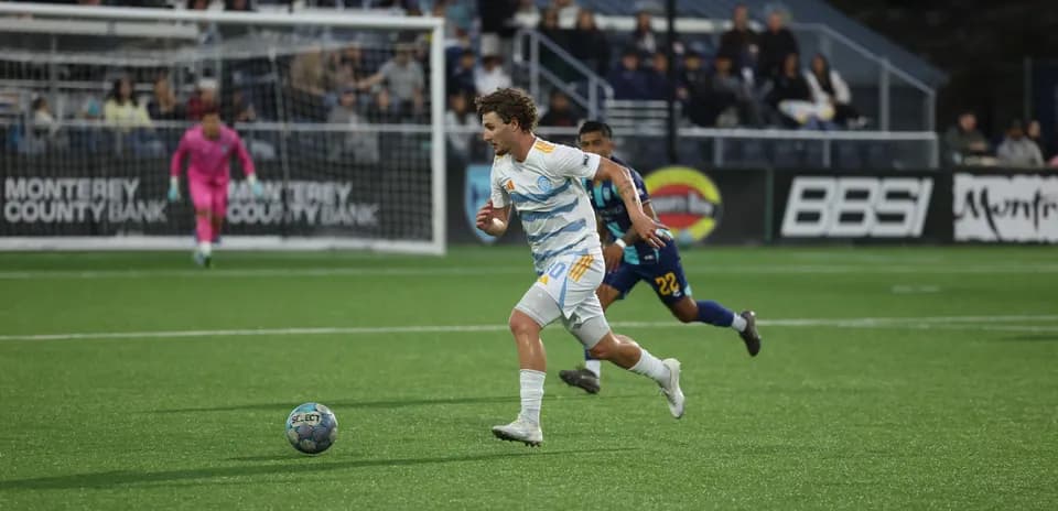 Player sprinting with ball during Monterey Bay match