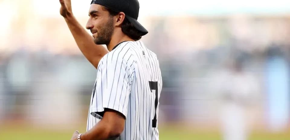 Man waving in Yankees jersey at baseball game