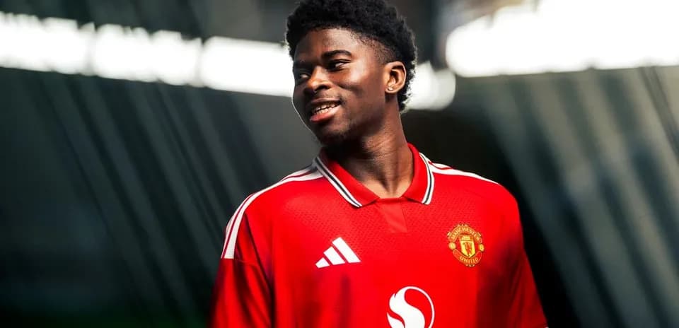Player in Manchester United jersey smiling during photoshoot