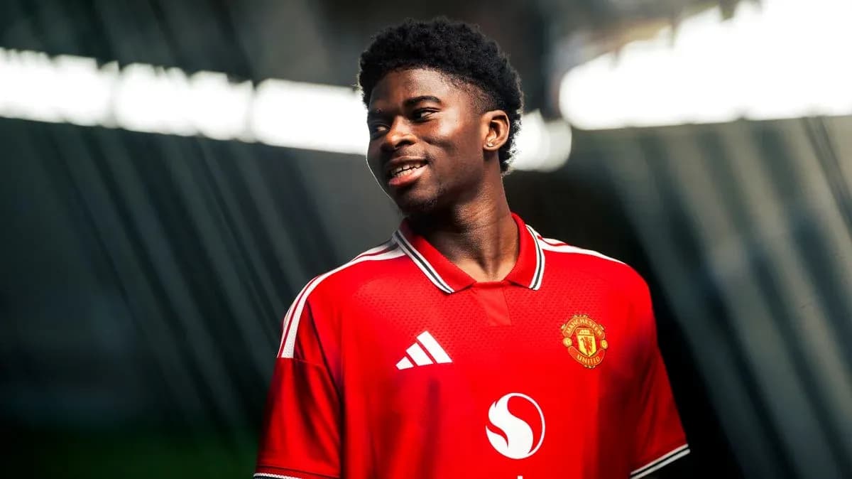 Player in Manchester United jersey smiling during photoshoot