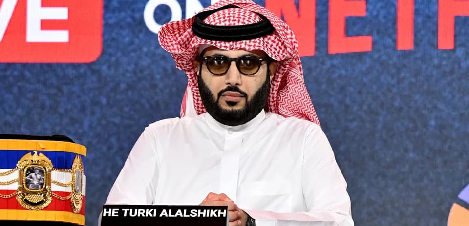 Man in traditional attire at press conference table