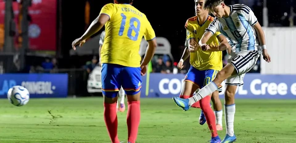 Argentinian player kicking ball against two defenders