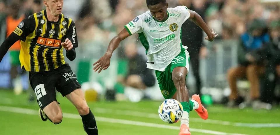Player in green dribbling past opponent in yellow