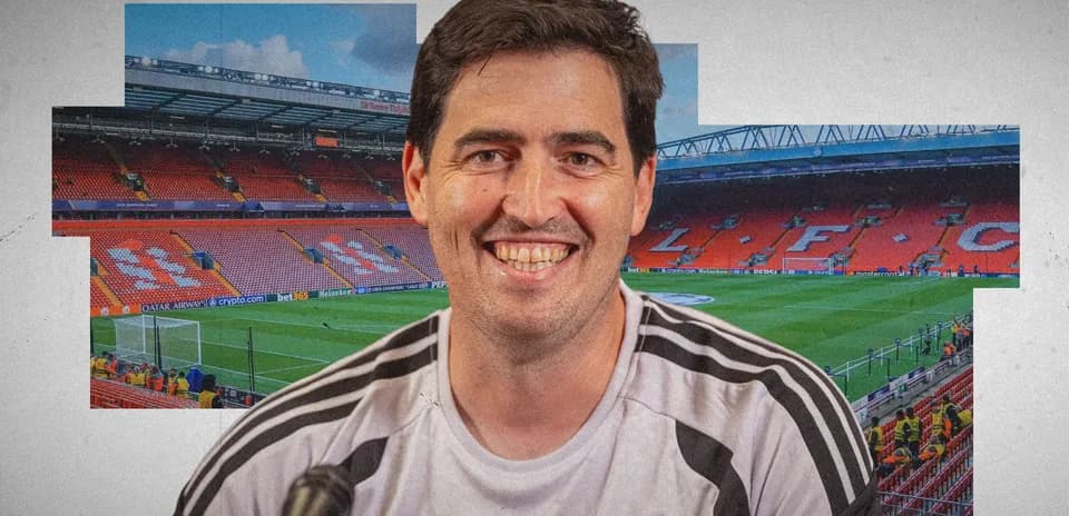 Coach smiling in front of Anfield stadium