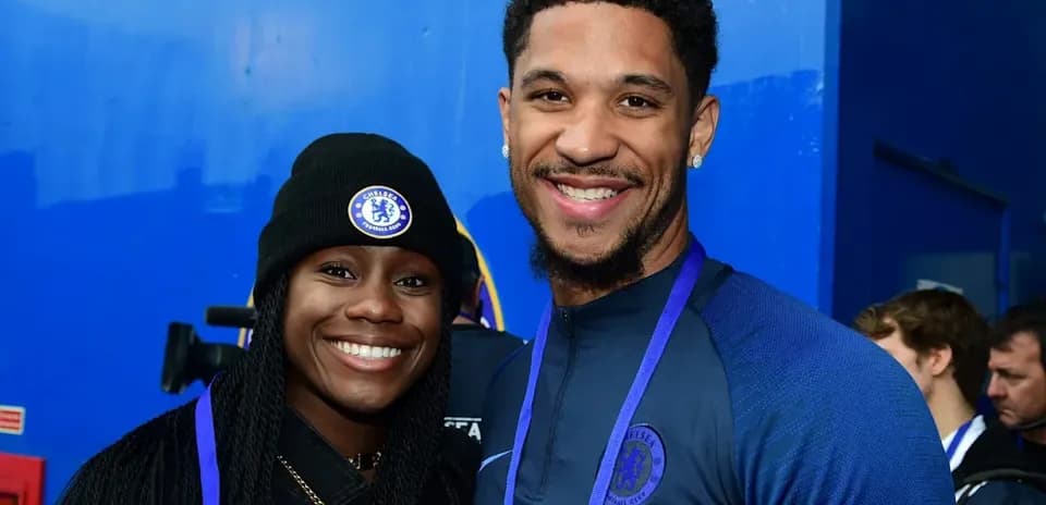 Two Chelsea FC fans posing together, smiling