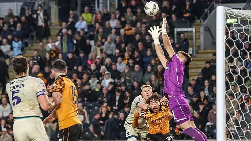 Goalkeeper jumping to catch the ball during match