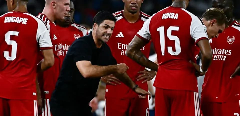 Arsenal players listening to coach during team huddle