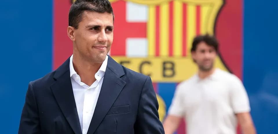 Man in suit standing in front of FC Barcelona logo