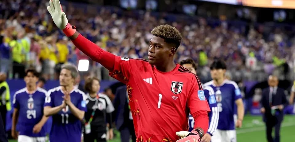 Goalkeeper in red jersey waving to fans after match