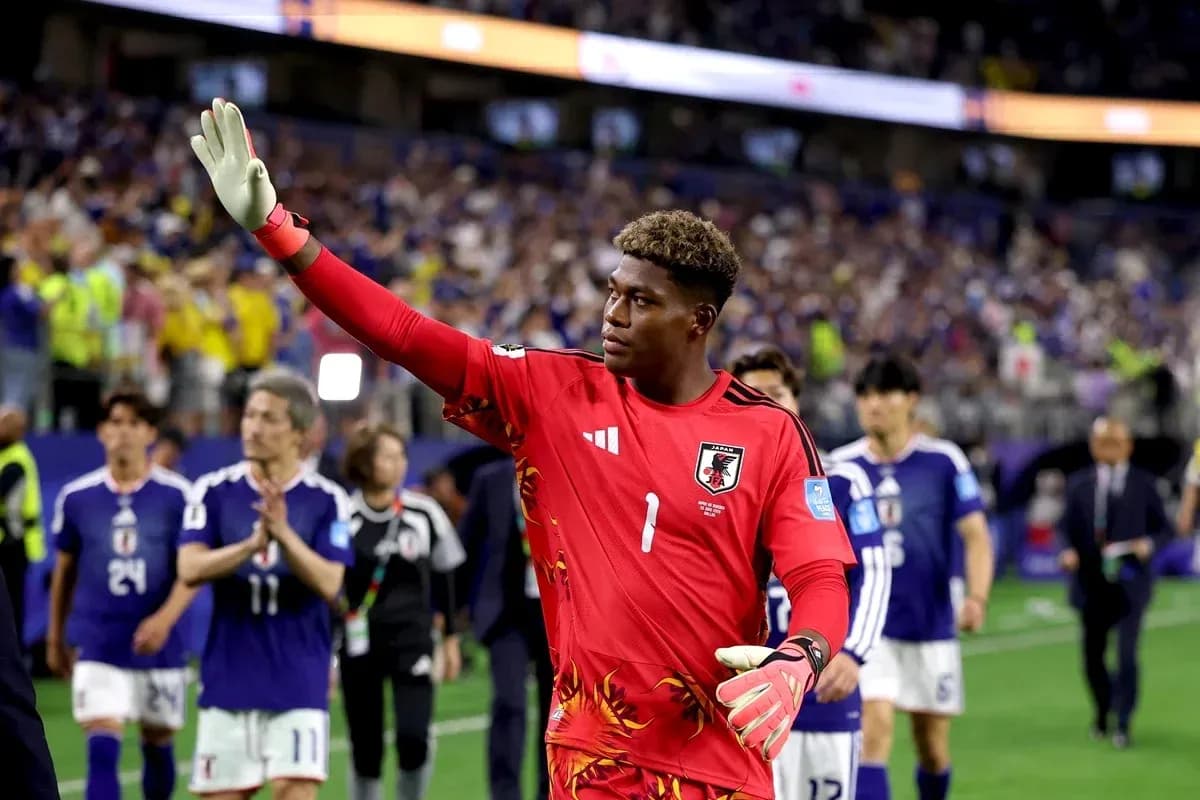 Goalkeeper in red jersey waving to fans after match