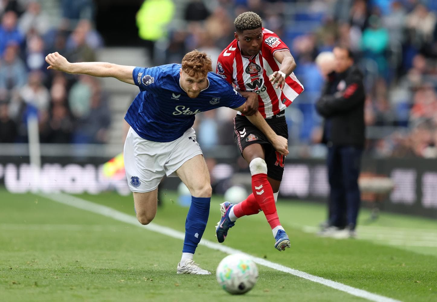 Everton player tackling Sunderland opponent in match