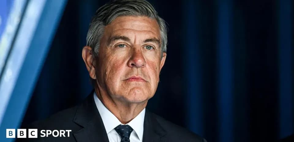 Man in a suit at a press conference backdrop