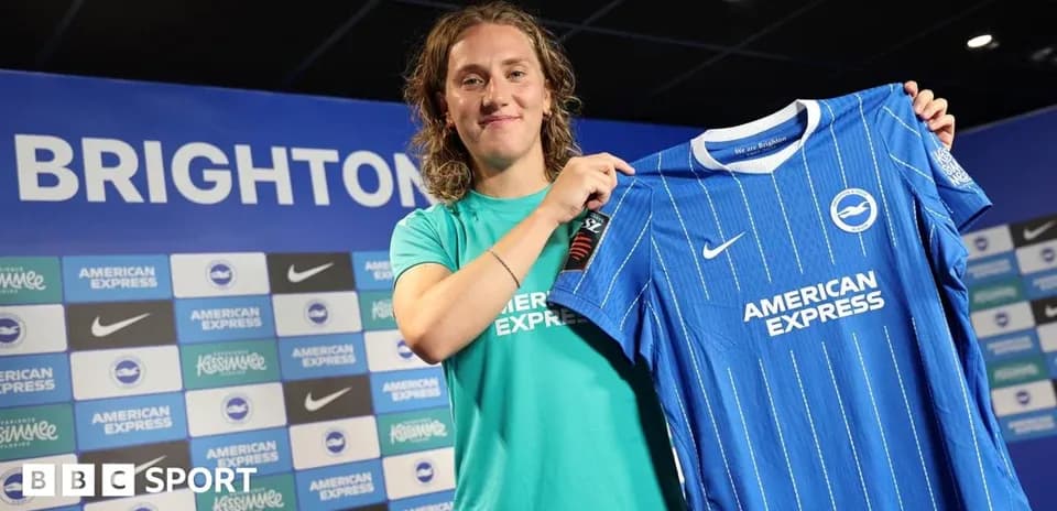 Player holding Brighton jersey at press conference