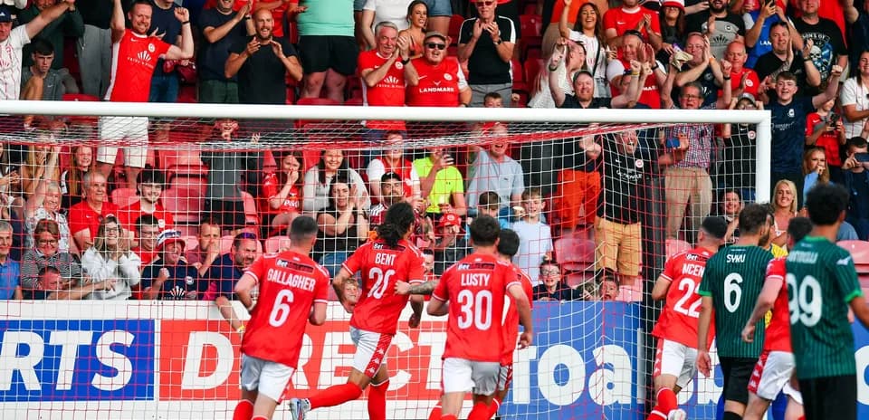 Players celebrating goal with cheering fans